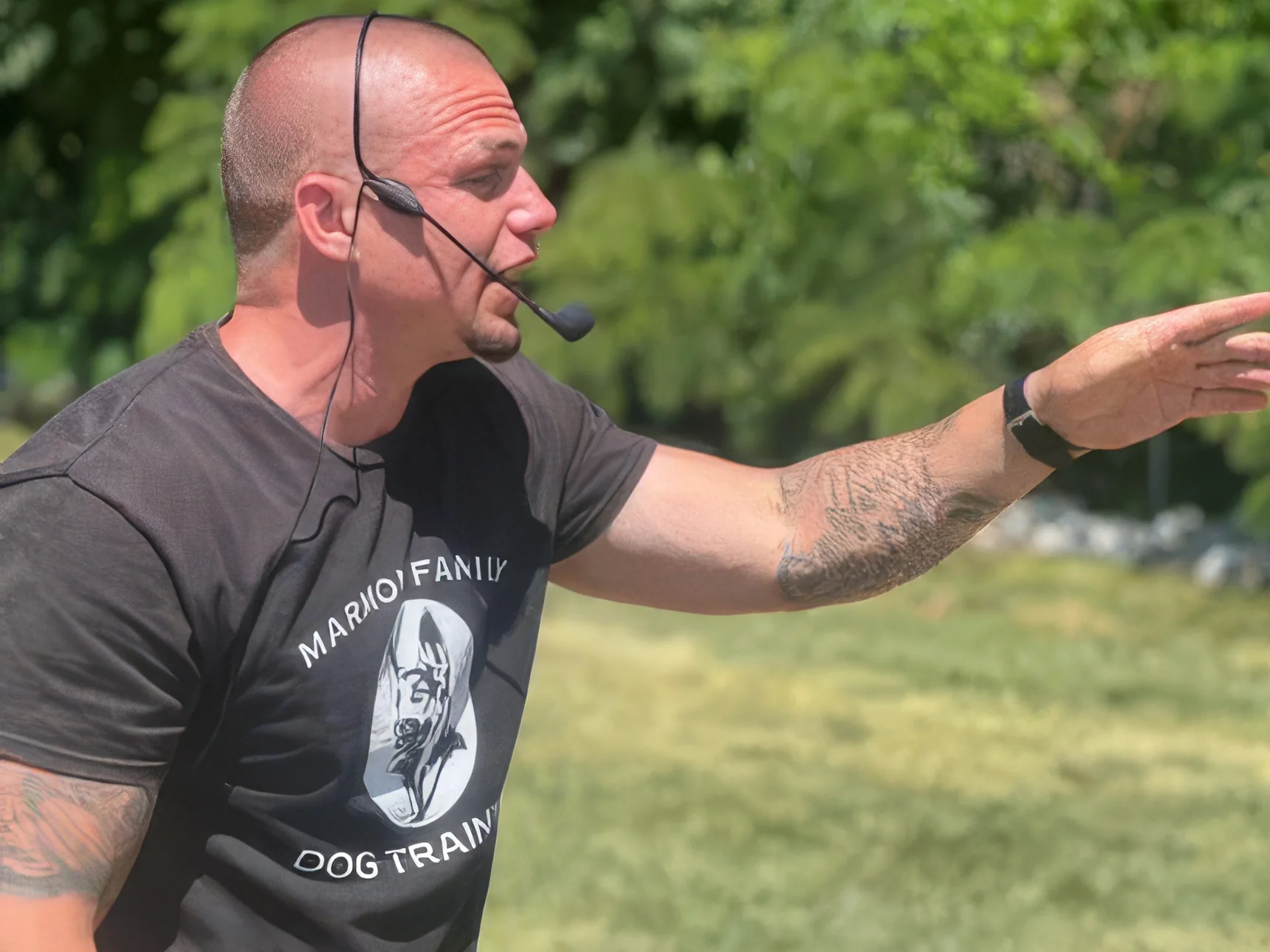 Aaron Marmon in a Marmon Family Dog Training shirt and headset giving a hand signal during a session